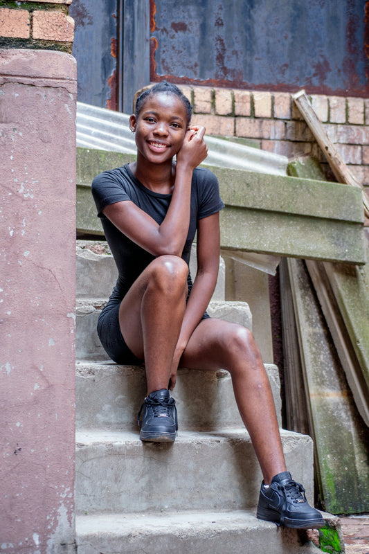woman in blue tank top and black shorts sitting on stairs